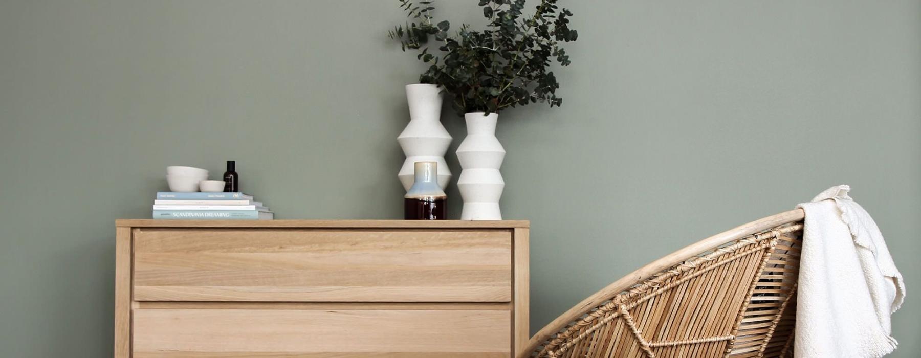 decor on a tall, wooden dresser next to a papasan chair with a throw